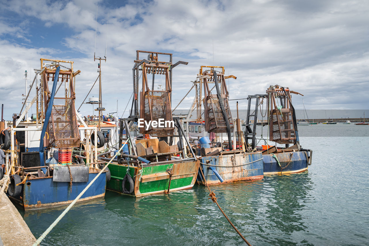 Four small fishing boats with shellfish cages moored in howth harbour, dublin, ireland