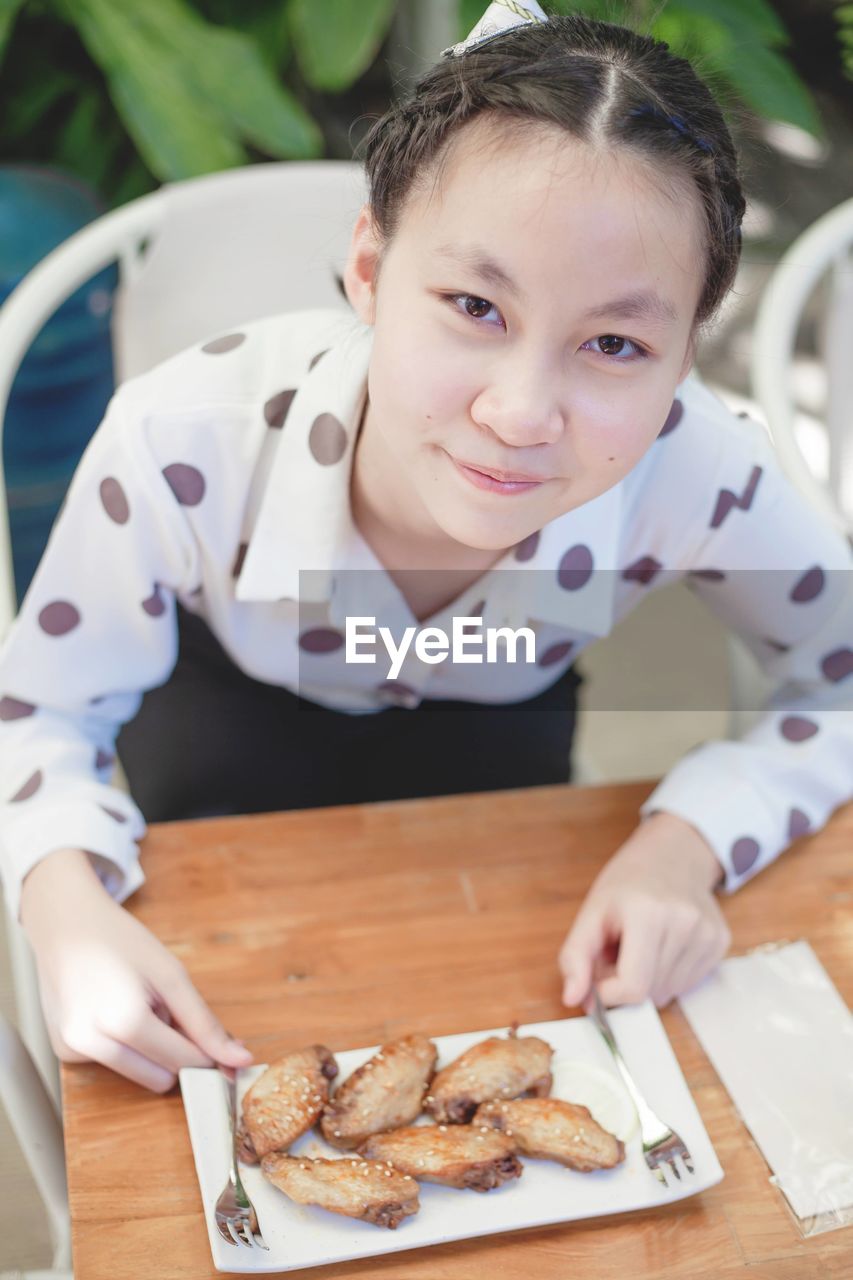 Portrait of girl eating food at cafe