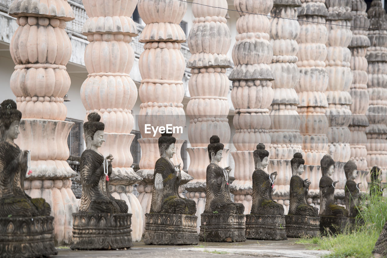 Old buddha statues in row by columns at temple