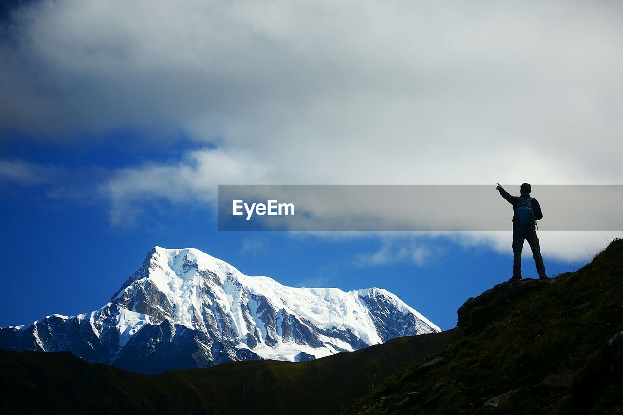 FULL LENGTH OF PERSON STANDING ON SNOWCAPPED MOUNTAIN AGAINST SKY