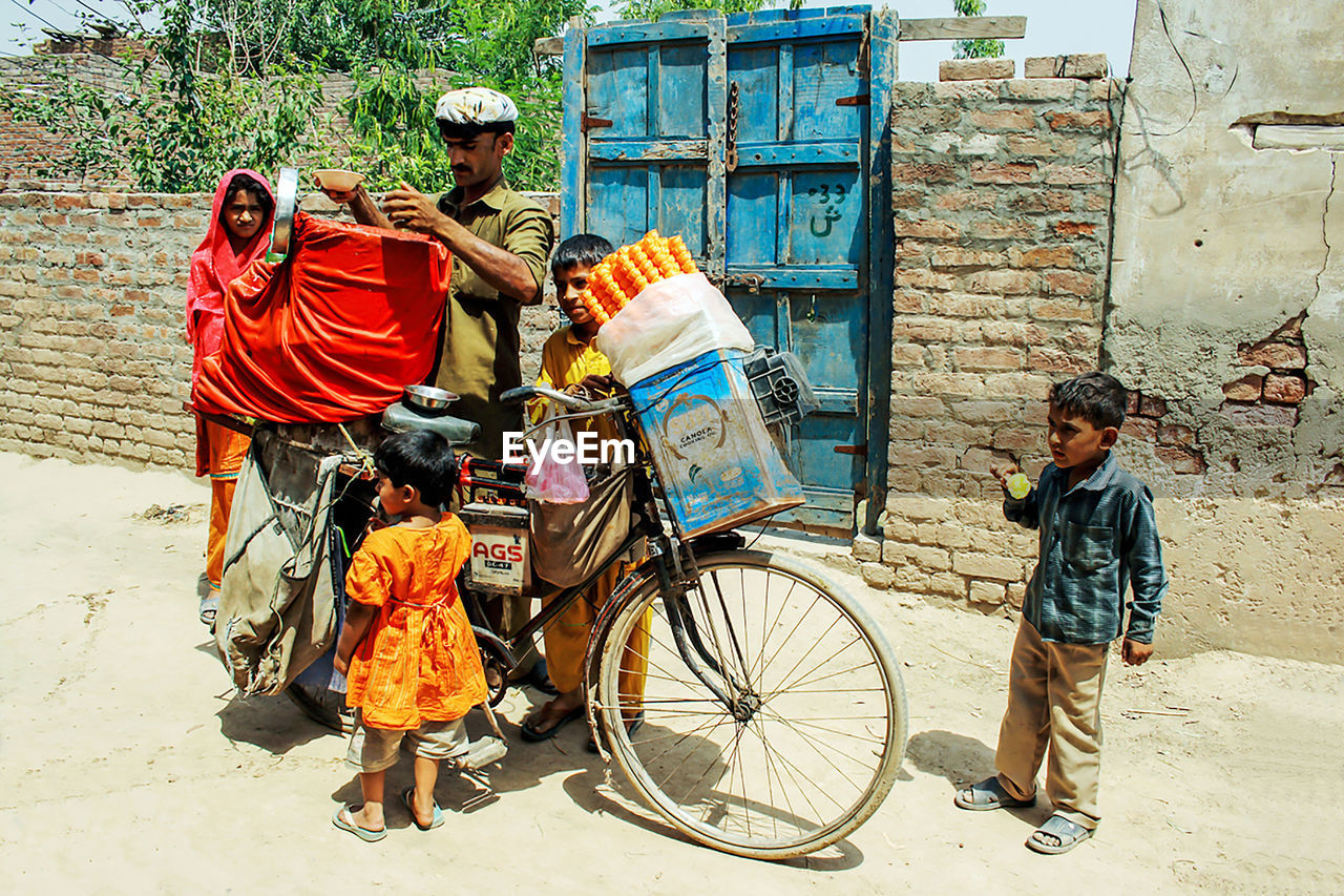 REAR VIEW OF PEOPLE WITH BICYCLE AGAINST WALL