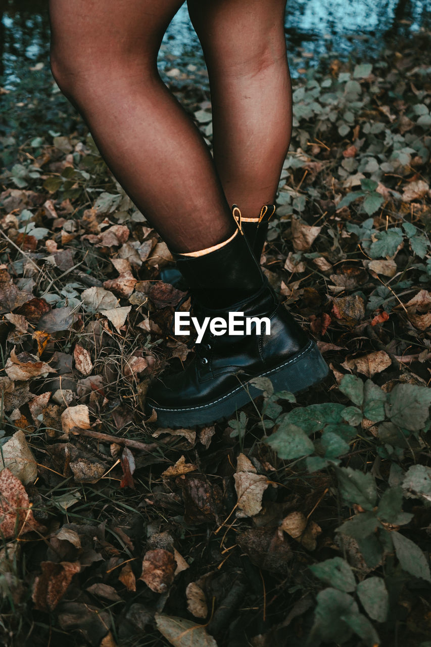 Low section of woman standing on ground during autumn