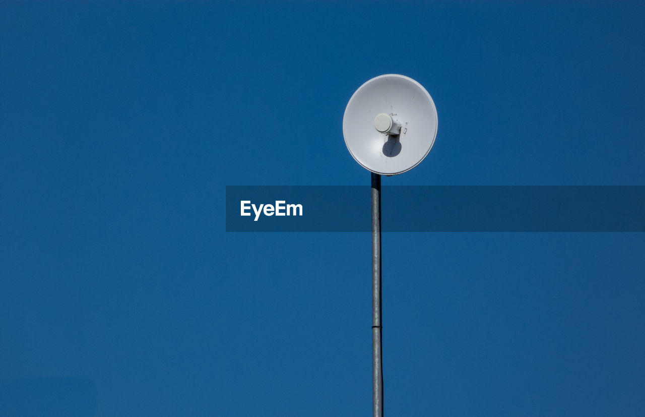 Low angle view of telephone pole against clear blue sky