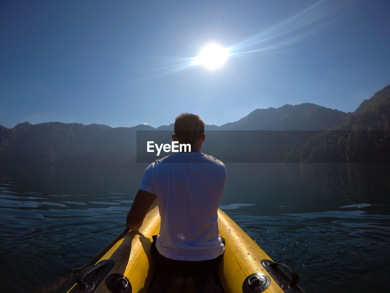 Rear view of man kayaking on river against sky