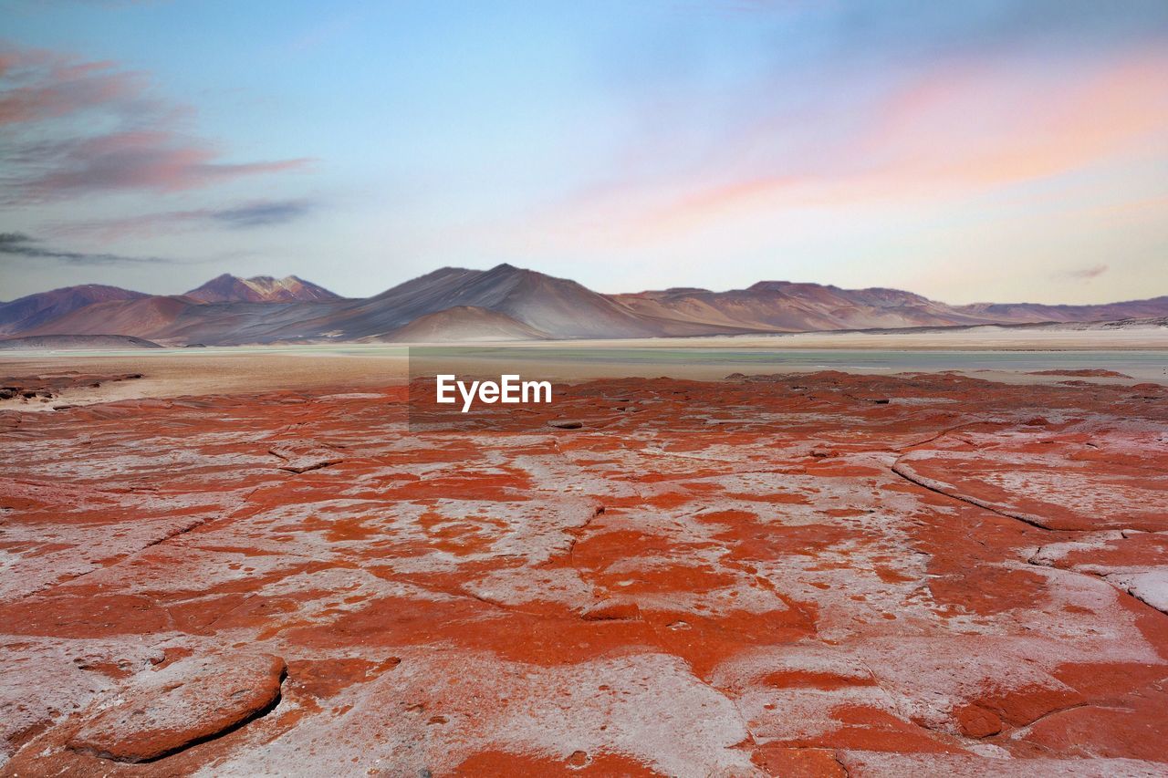 Red rocks on field against sky during sunset