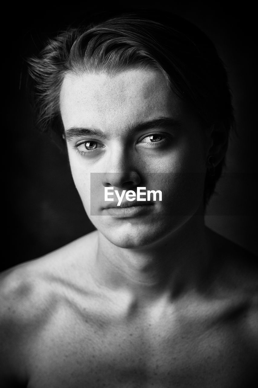 Close-up portrait of handsome young man against black background