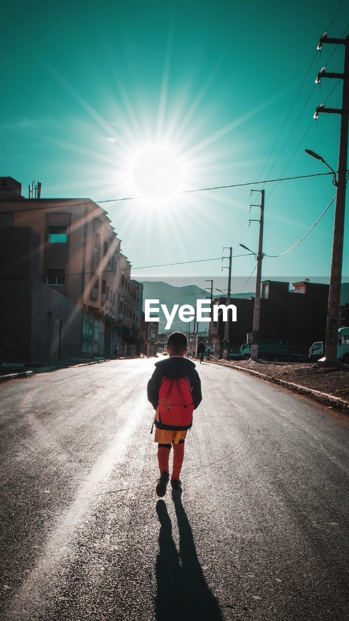 Rear view of man on street against bright sun