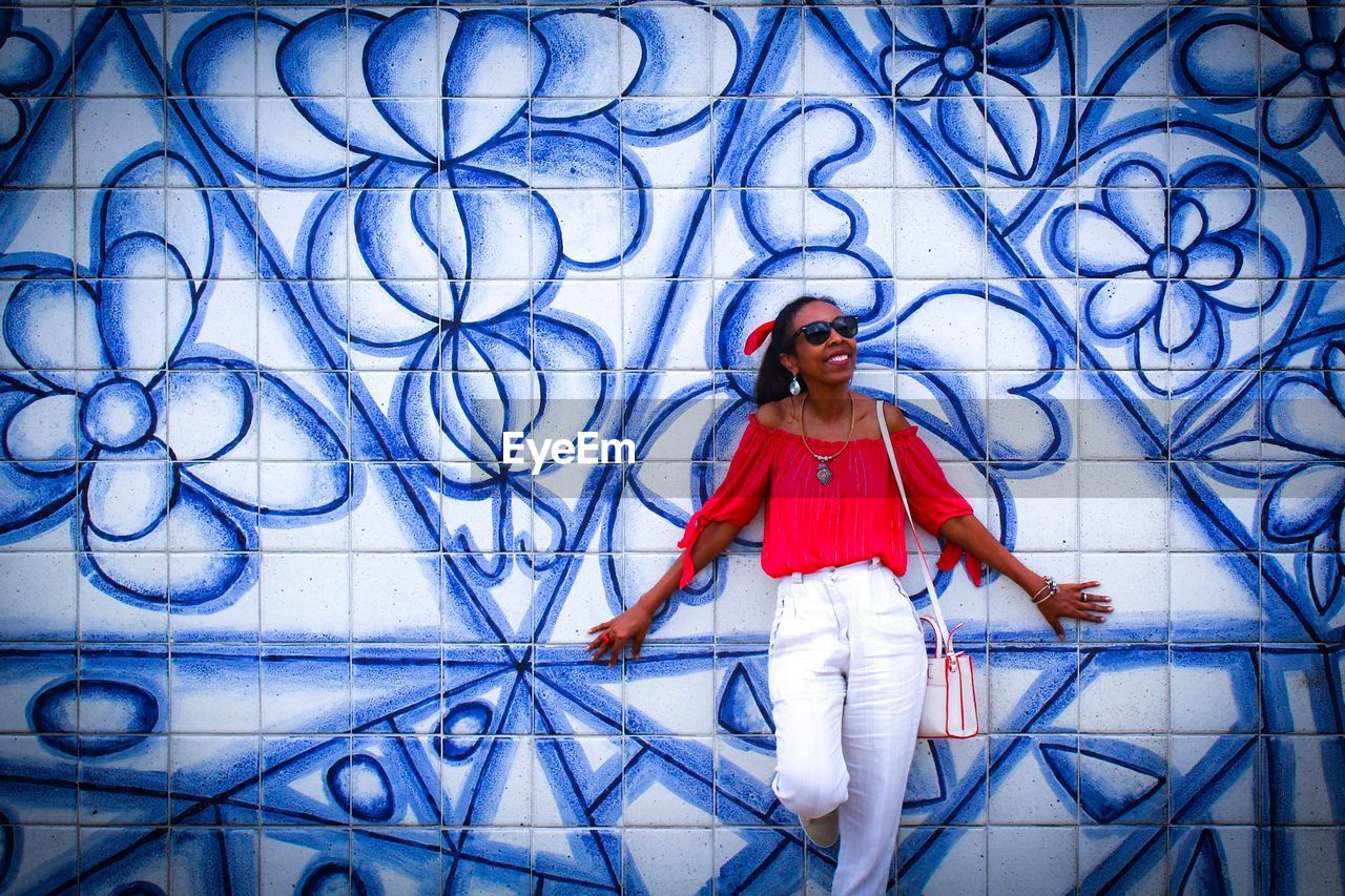 Smiling woman standing against blue patterned tile wall