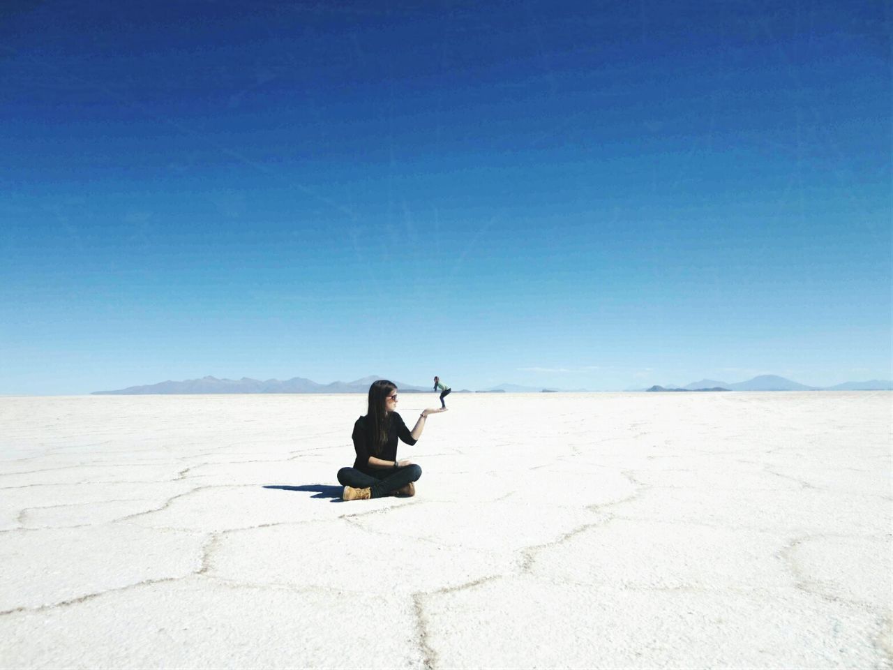 Optical illusion of woman holding friend at salar de uyuni against sky