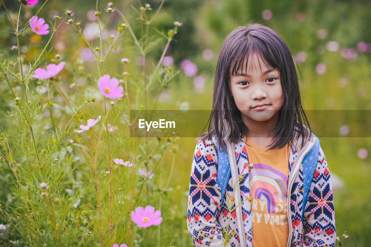 Portrait of a young girl standing amidst plants