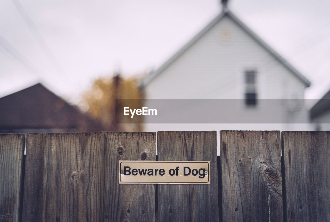 Close-up of beware of dog sign on fence
