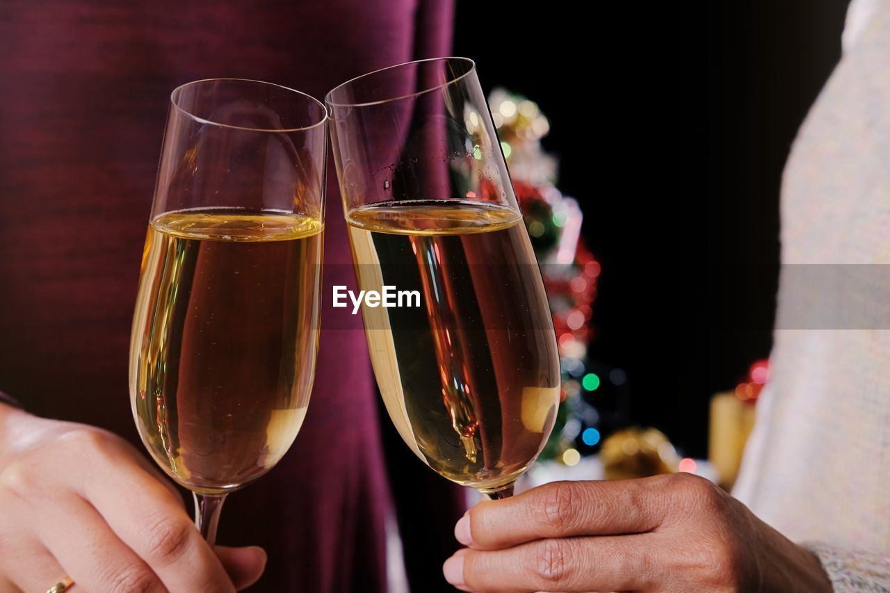 Midsection of couple toasting champions flutes during christmas 