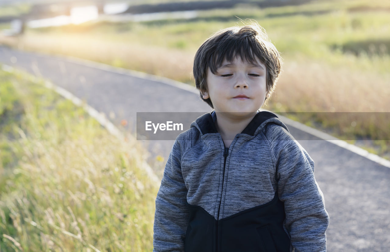 Boy with eyes closed standing on land