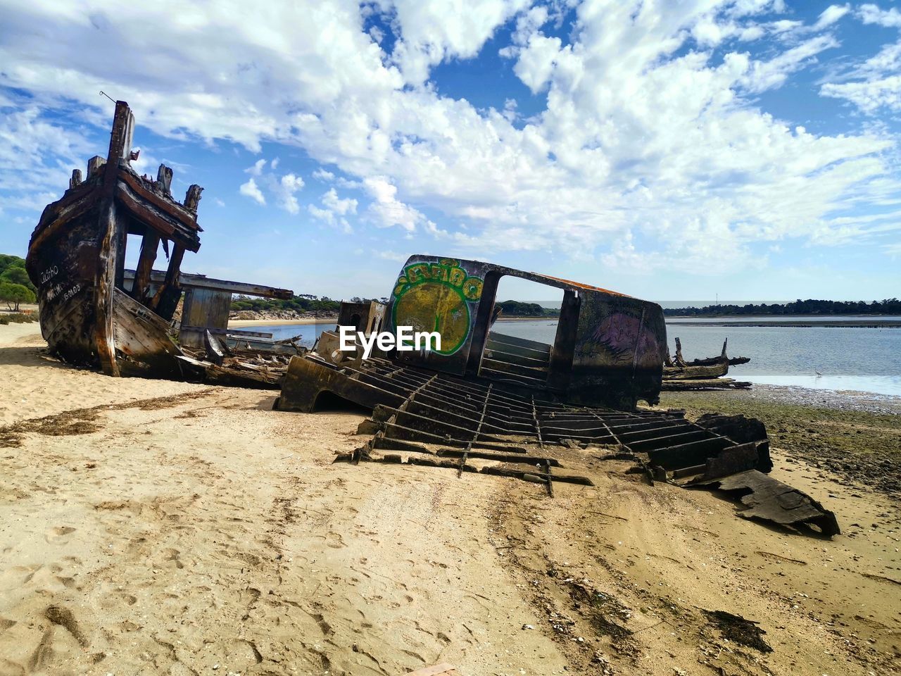 ABANDONED BOAT ON SHORE AGAINST SKY