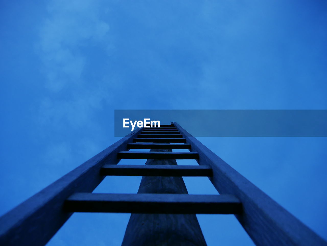 Low angle view of ladder leading towards blue sky at dusk