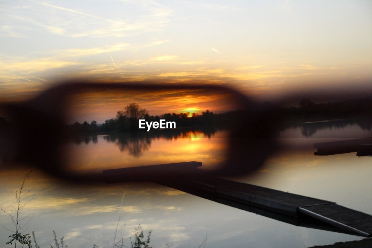 REFLECTION OF TREES IN LAKE DURING SUNSET