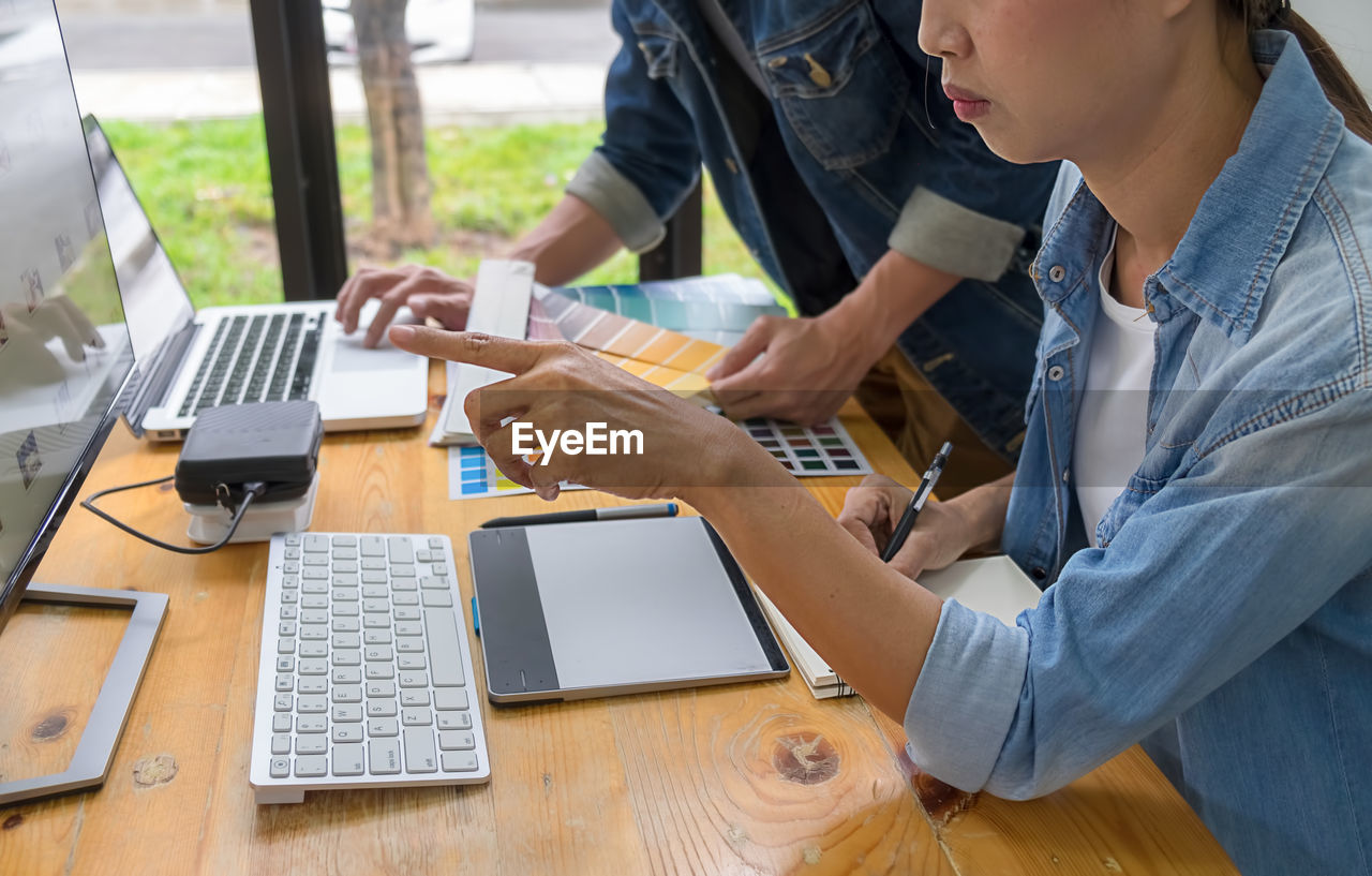 REAR VIEW OF PEOPLE WORKING ON TABLE IN OFFICE