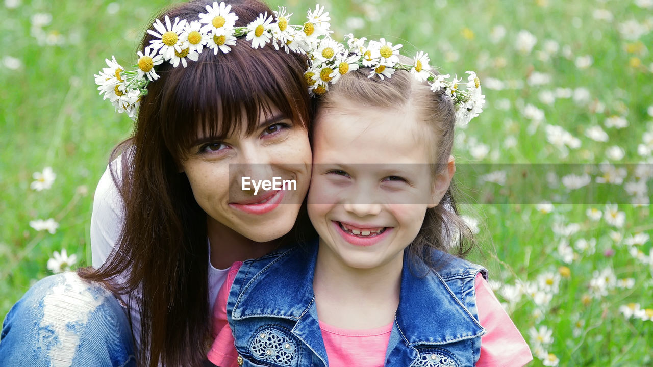 Summer, amidst a chamomile lawn, in the forest, a young woman, a brunette and a girl of seven