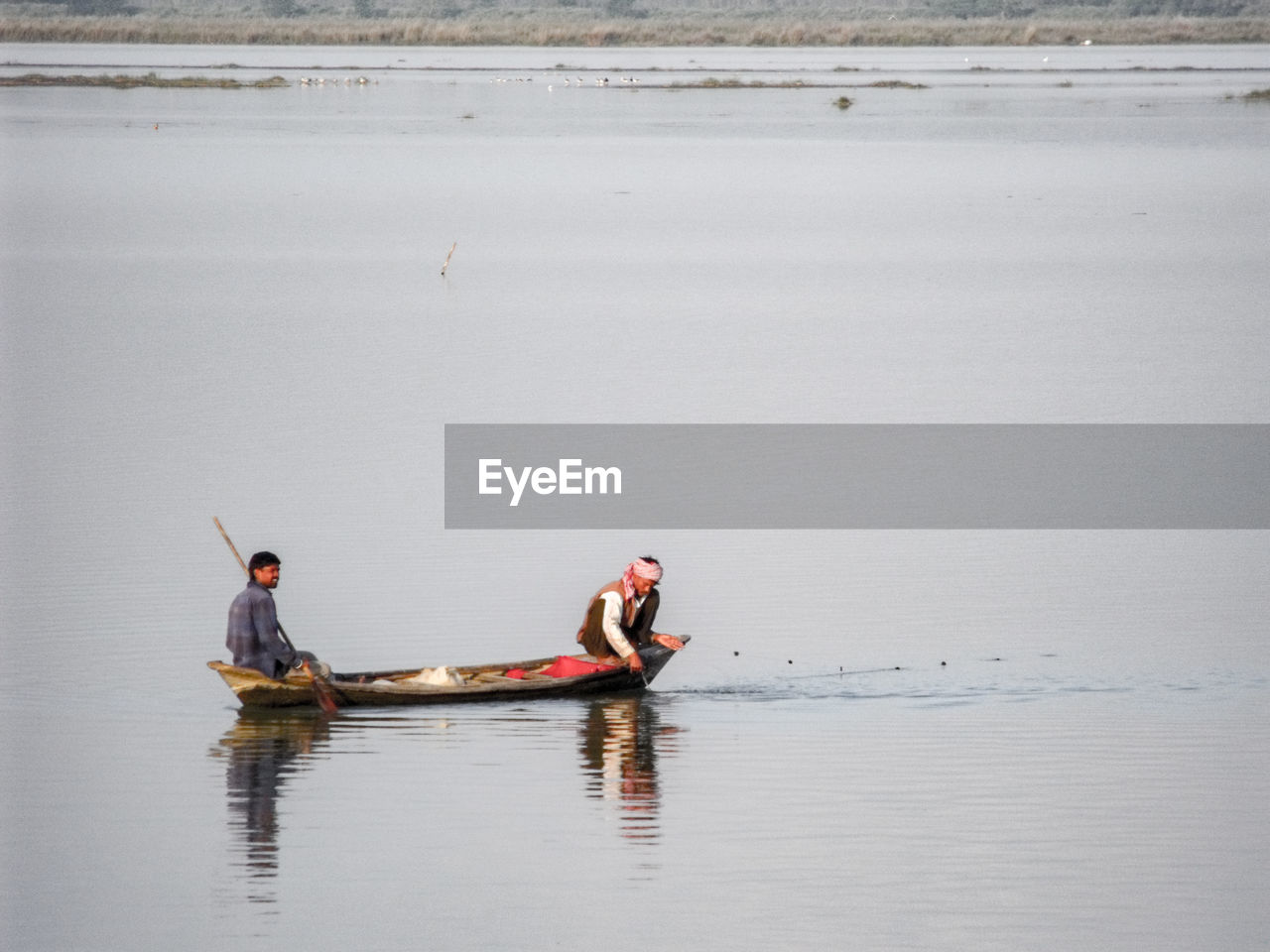 Men sitting in fishing boat on lake