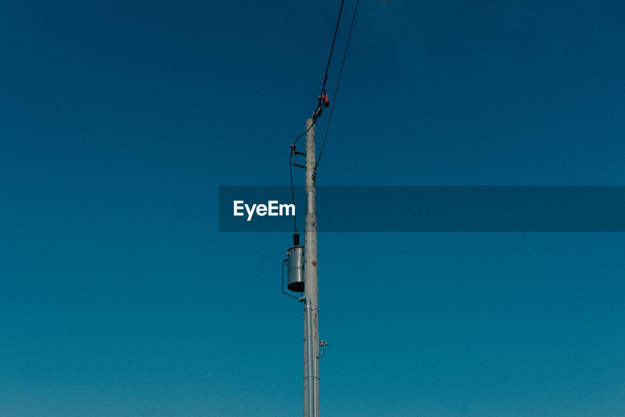 LOW ANGLE VIEW OF CRANES AGAINST CLEAR BLUE SKY