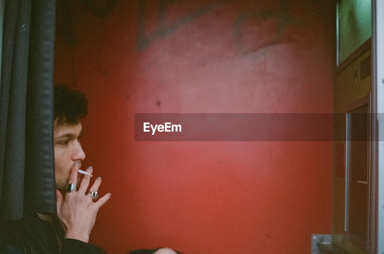 SIDE VIEW OF A YOUNG MAN SMOKING CIGARETTE