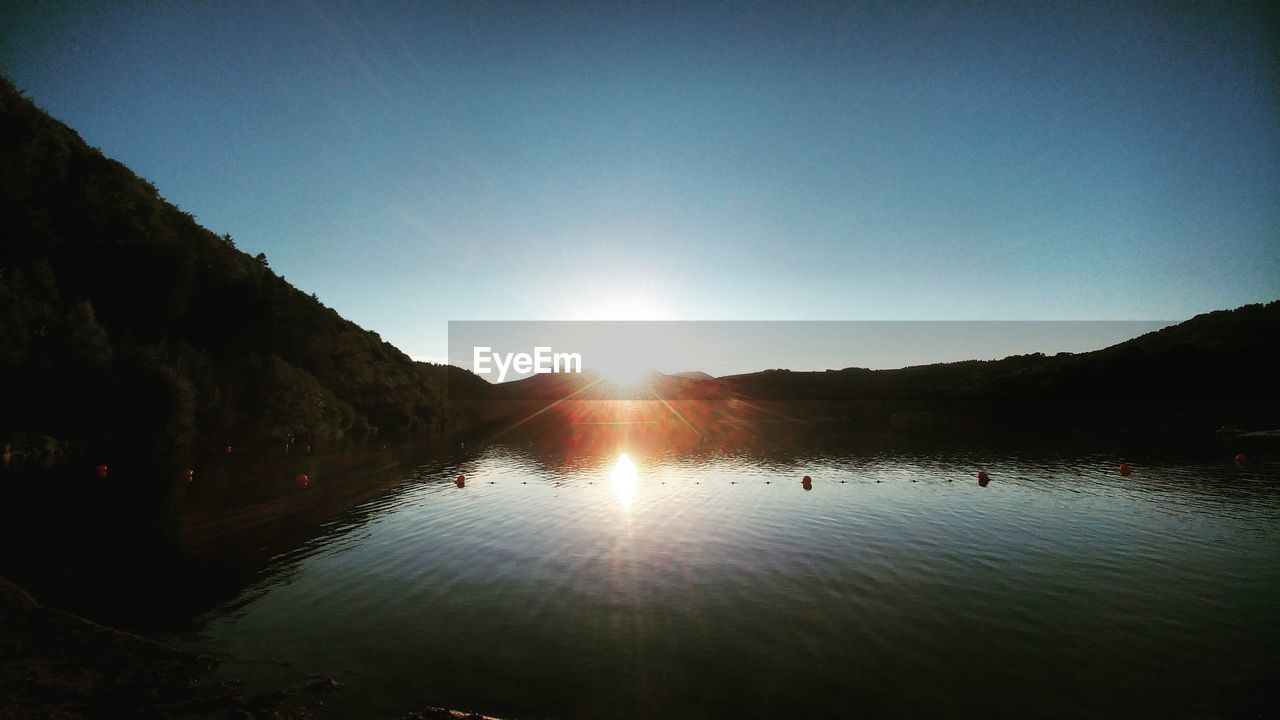 SCENIC VIEW OF LAKE BY MOUNTAINS AGAINST CLEAR SKY