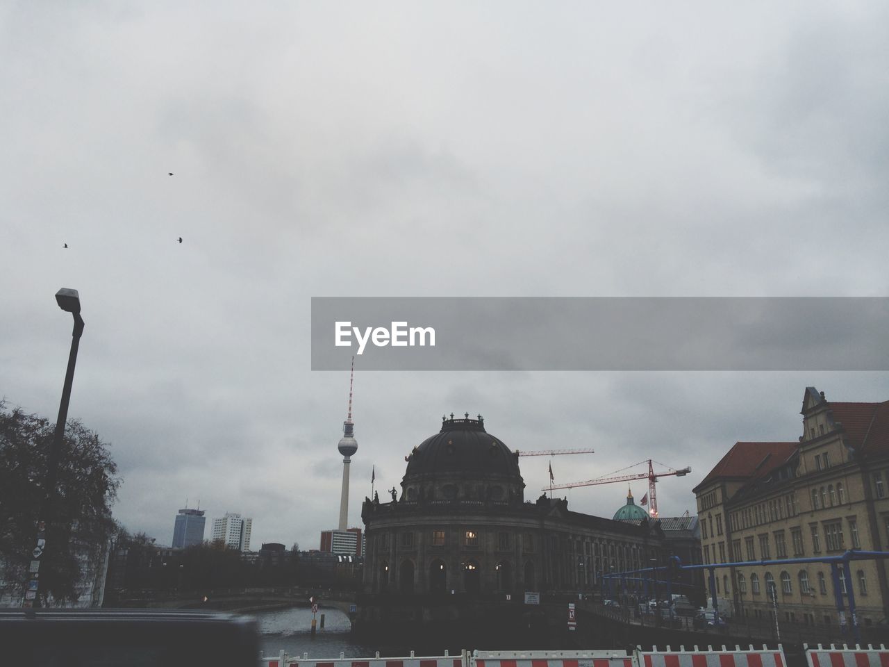 Fernsehturm and buildings against cloudy sky