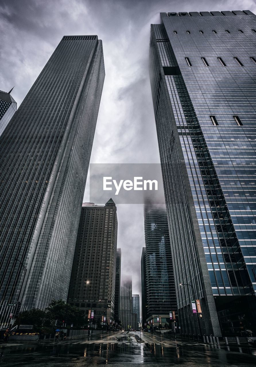 Low angle view of skyscrapers against cloudy sky