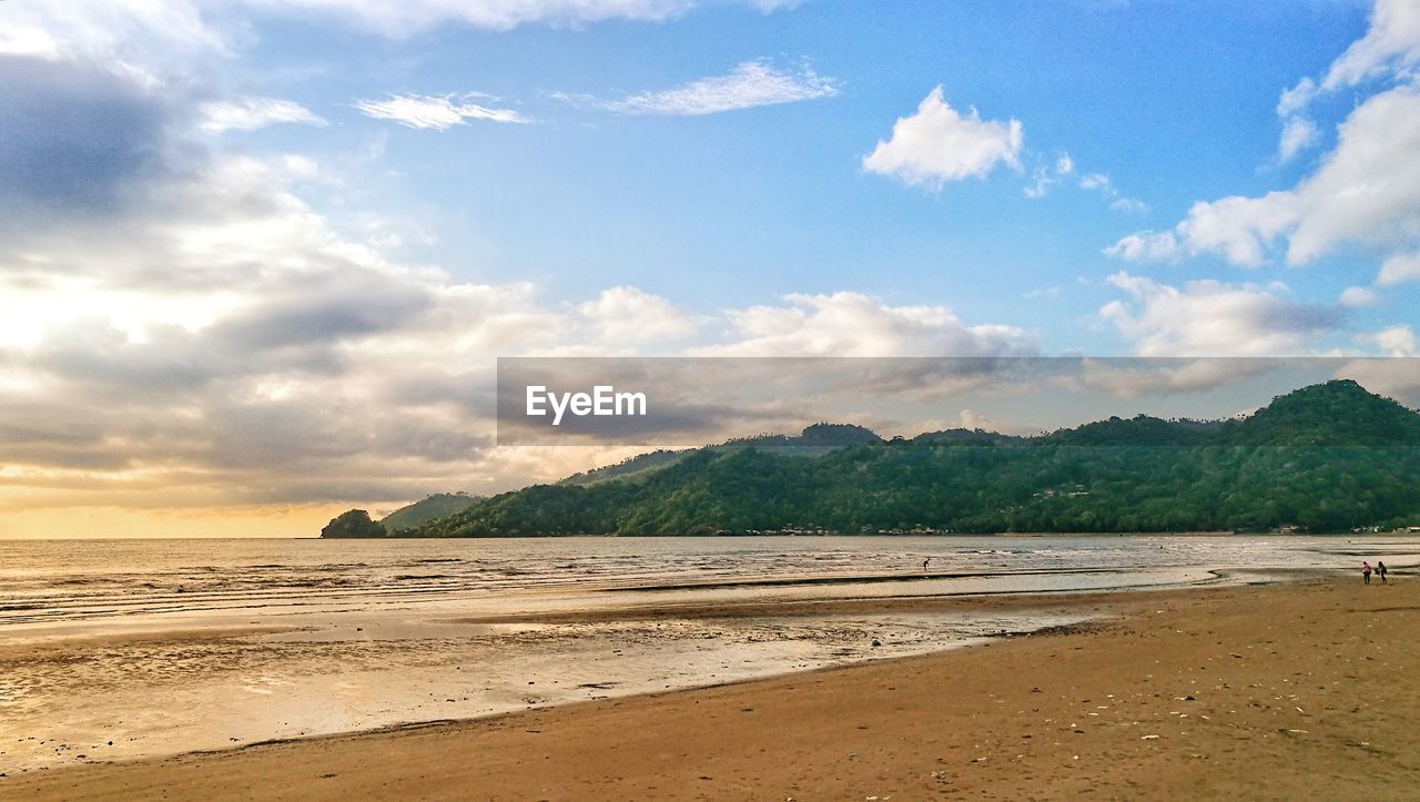 SCENIC VIEW OF BEACH AGAINST CLOUDY SKY