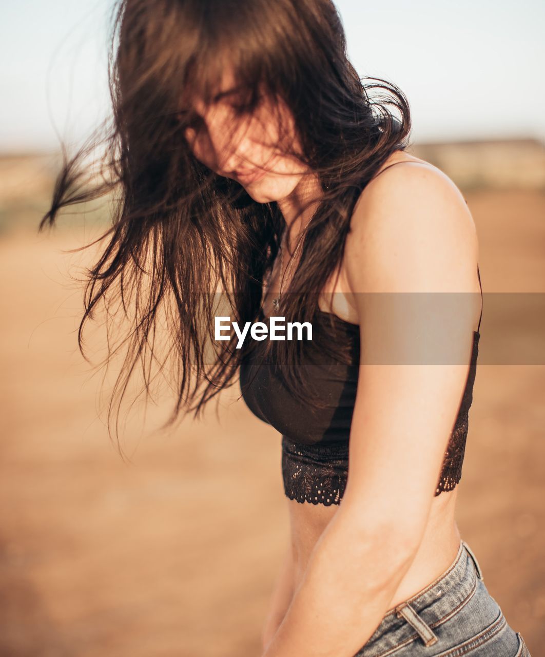 Young woman with tousled hair standing on land