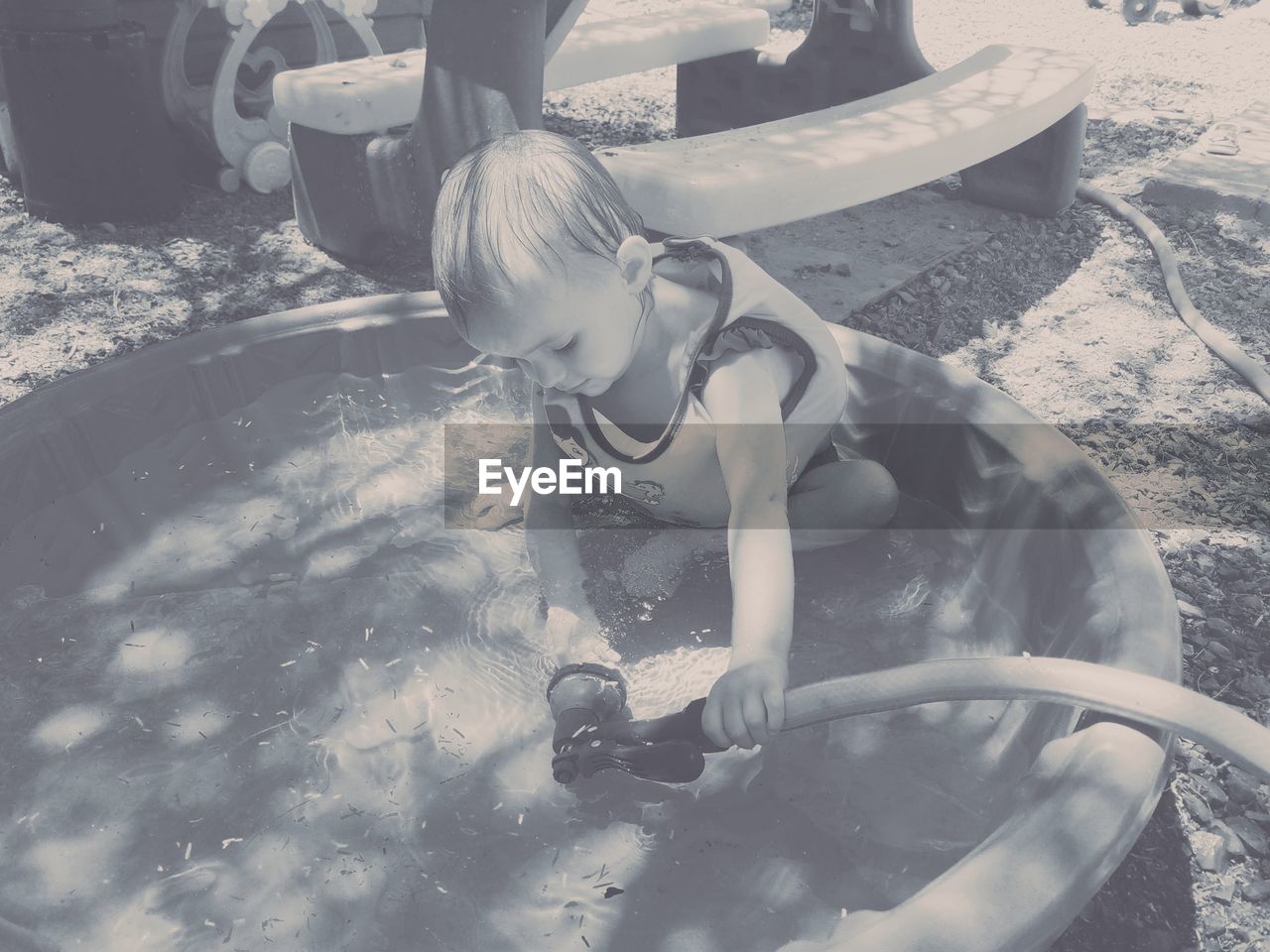 HIGH ANGLE VIEW OF GIRL SITTING AT SWIMMING POOL