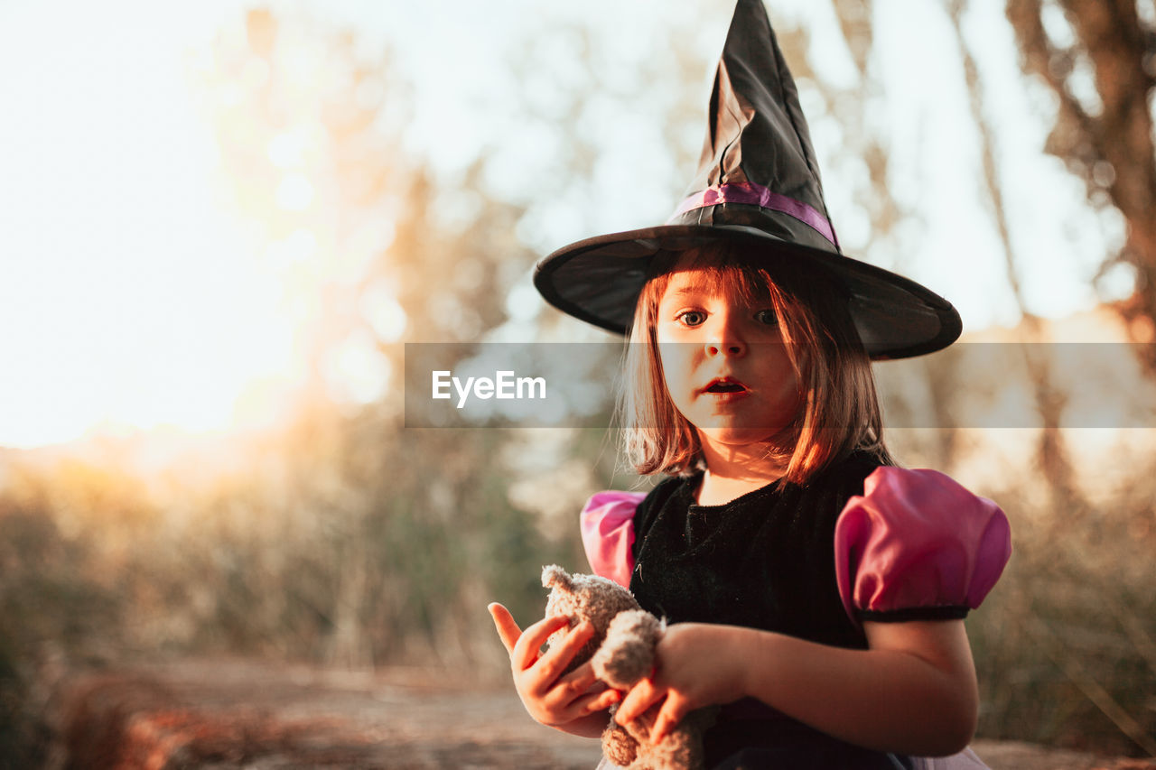 Portrait of girl wearing witchs hat during halloween at forest