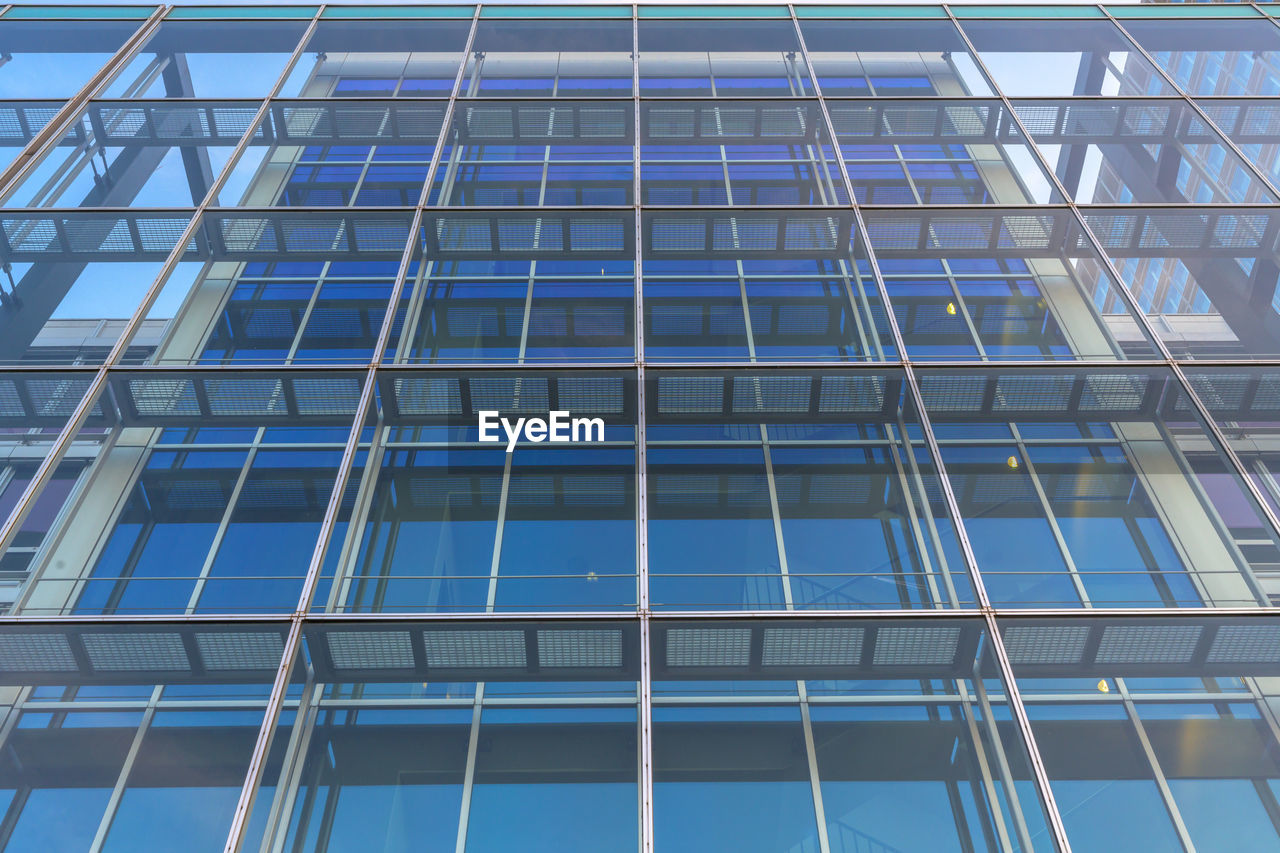 LOW ANGLE VIEW OF GLASS BUILDING WITH REFLECTION