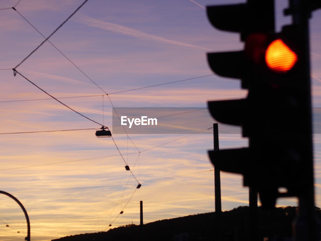 LOW ANGLE VIEW OF SILHOUETTE POWER LINES AGAINST ORANGE SKY