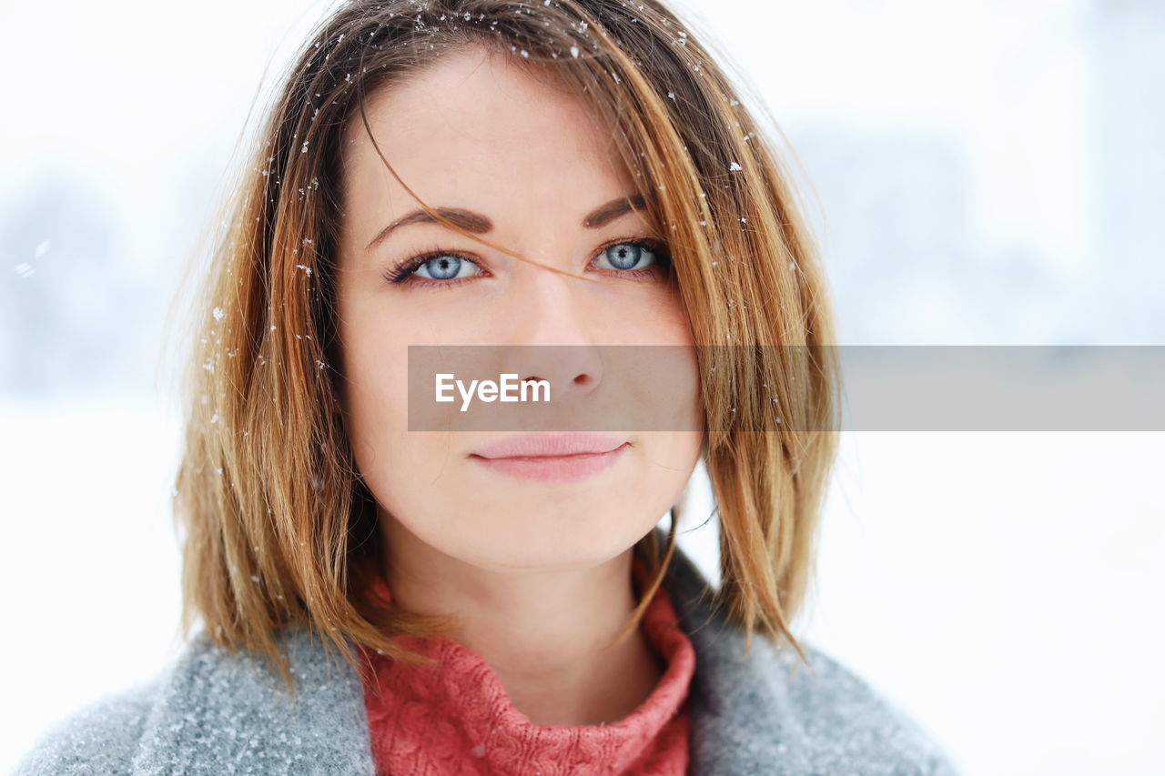 Close-up portrait of smiling young woman standing outdoors during winter