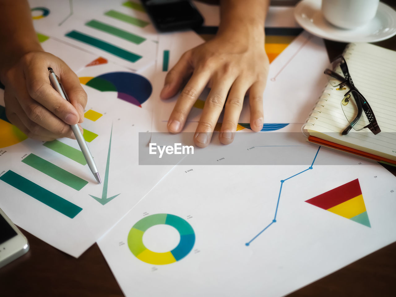 Cropped hand of business person working over graph in office