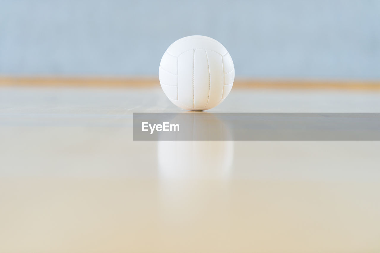 CLOSE-UP OF WHITE BALL ON TABLE AGAINST THE WALL