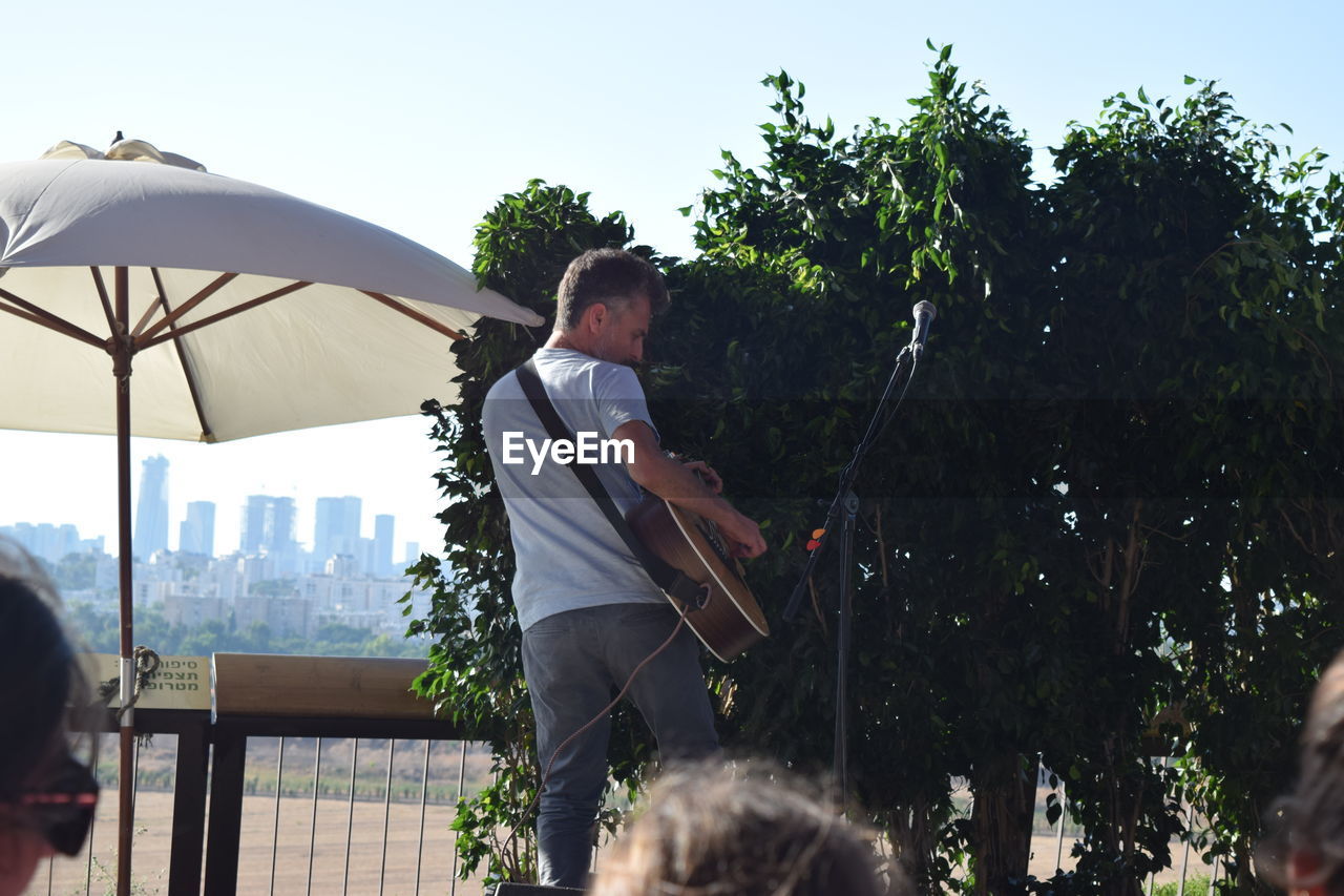 LOW ANGLE VIEW OF WOMAN STANDING ON TREE TRUNK