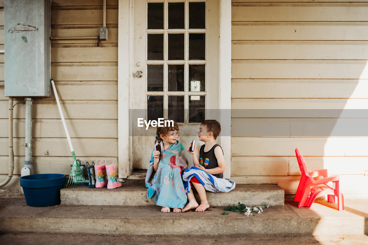 Young brother and sitting sitting on back porch eating ice cream