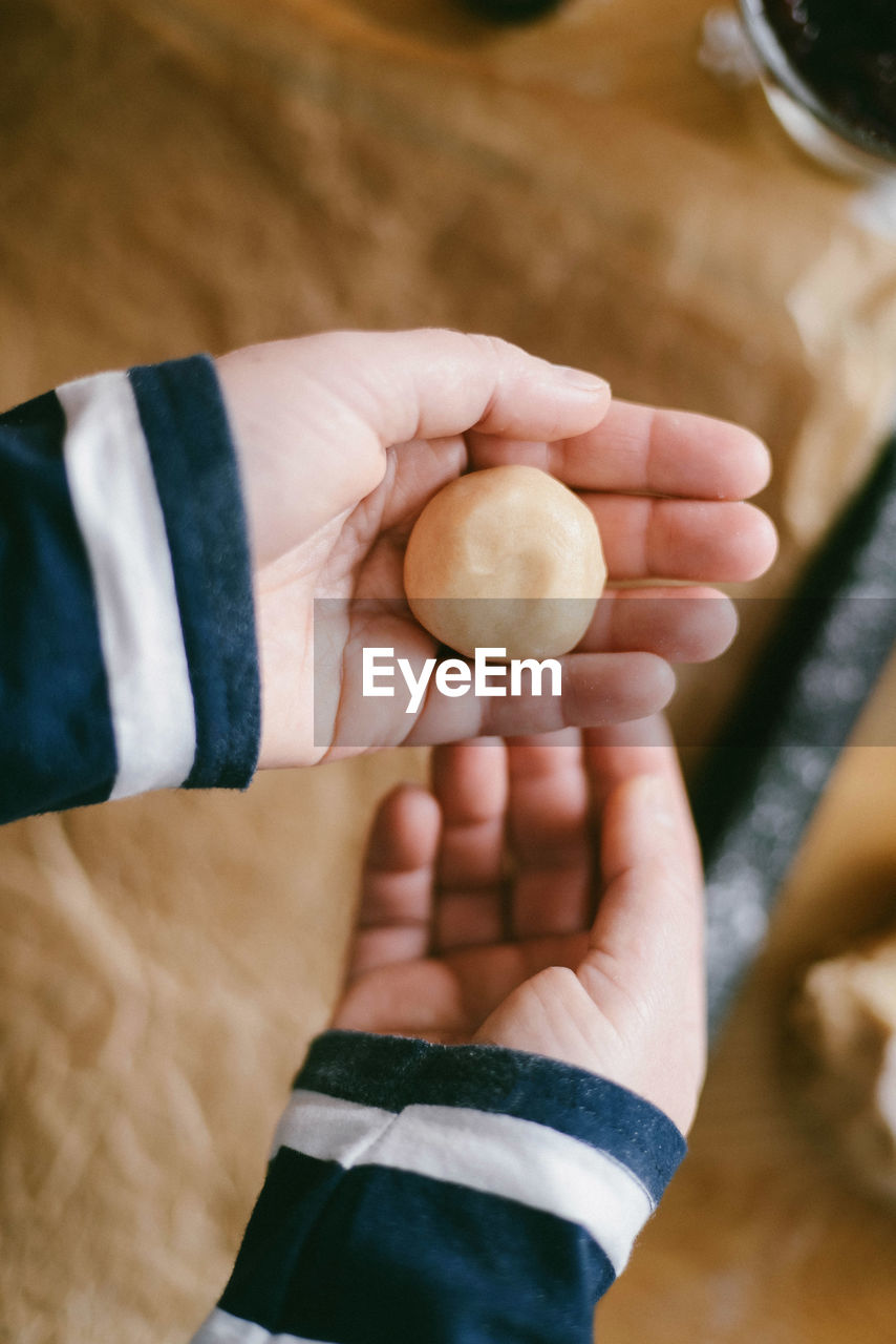 Cropped hand of woman holding dough at home