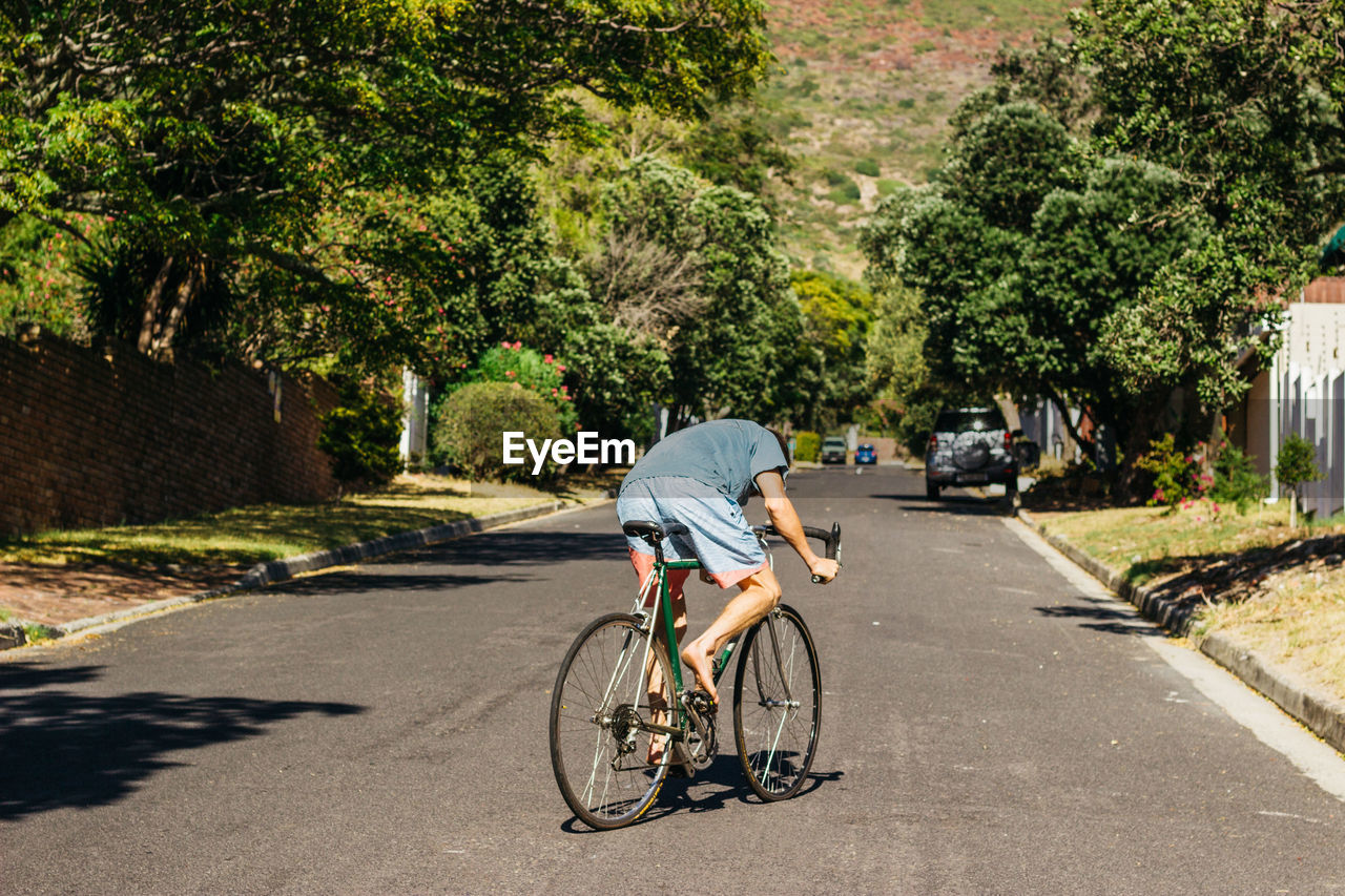 Rear view of man riding bicycle on road