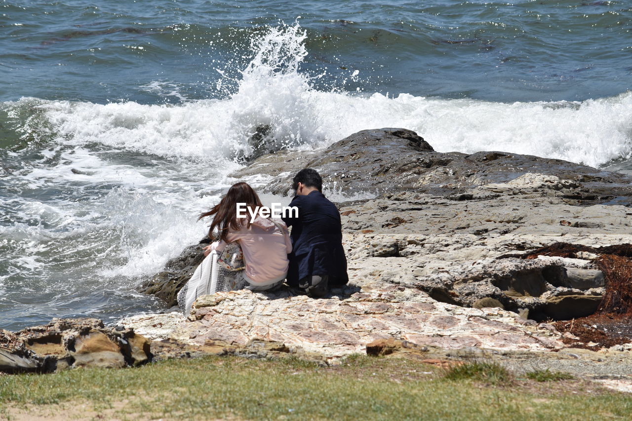 Couple sitting on rock at beach