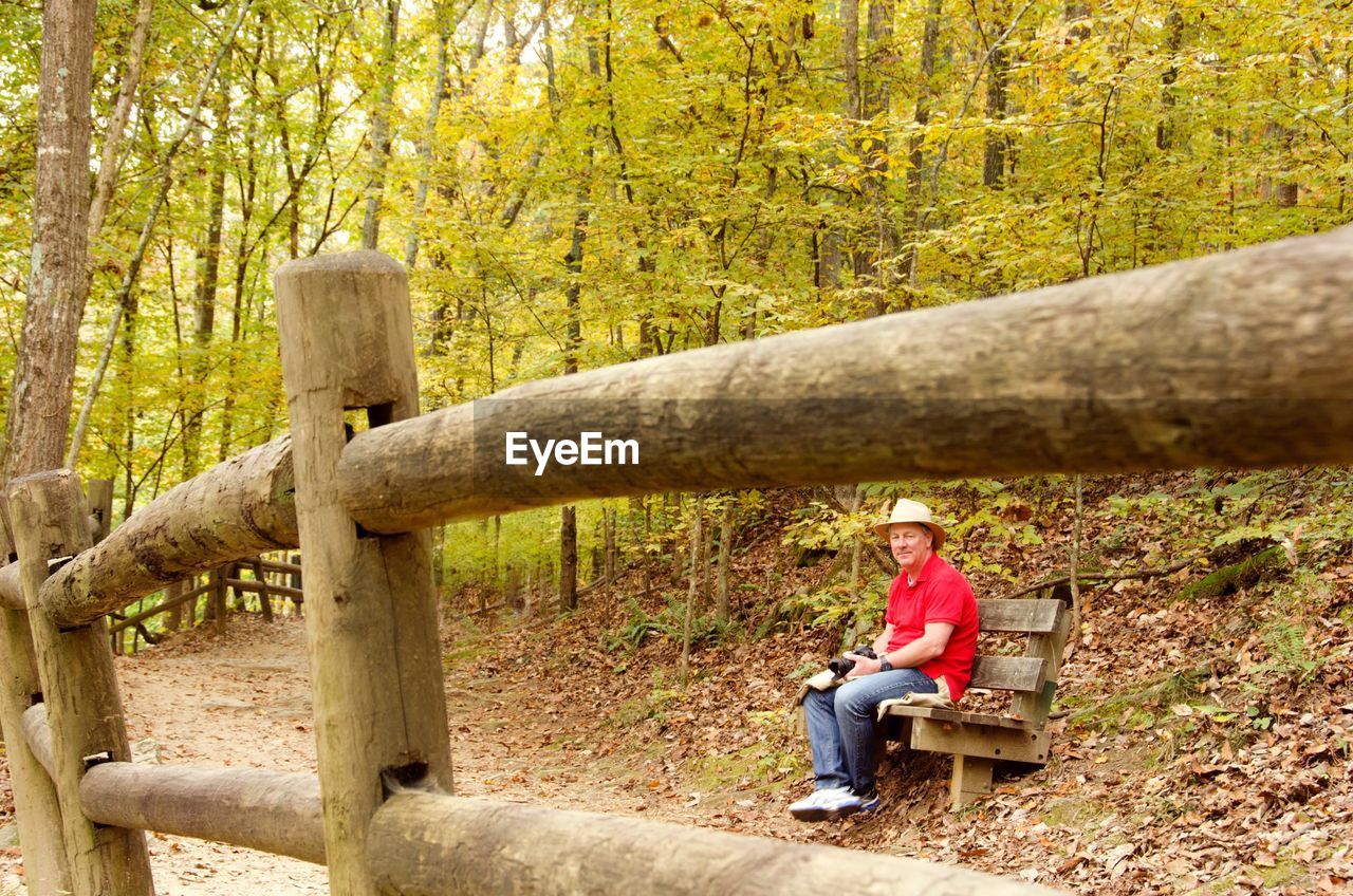 Man sitting on bench by walkway in forest