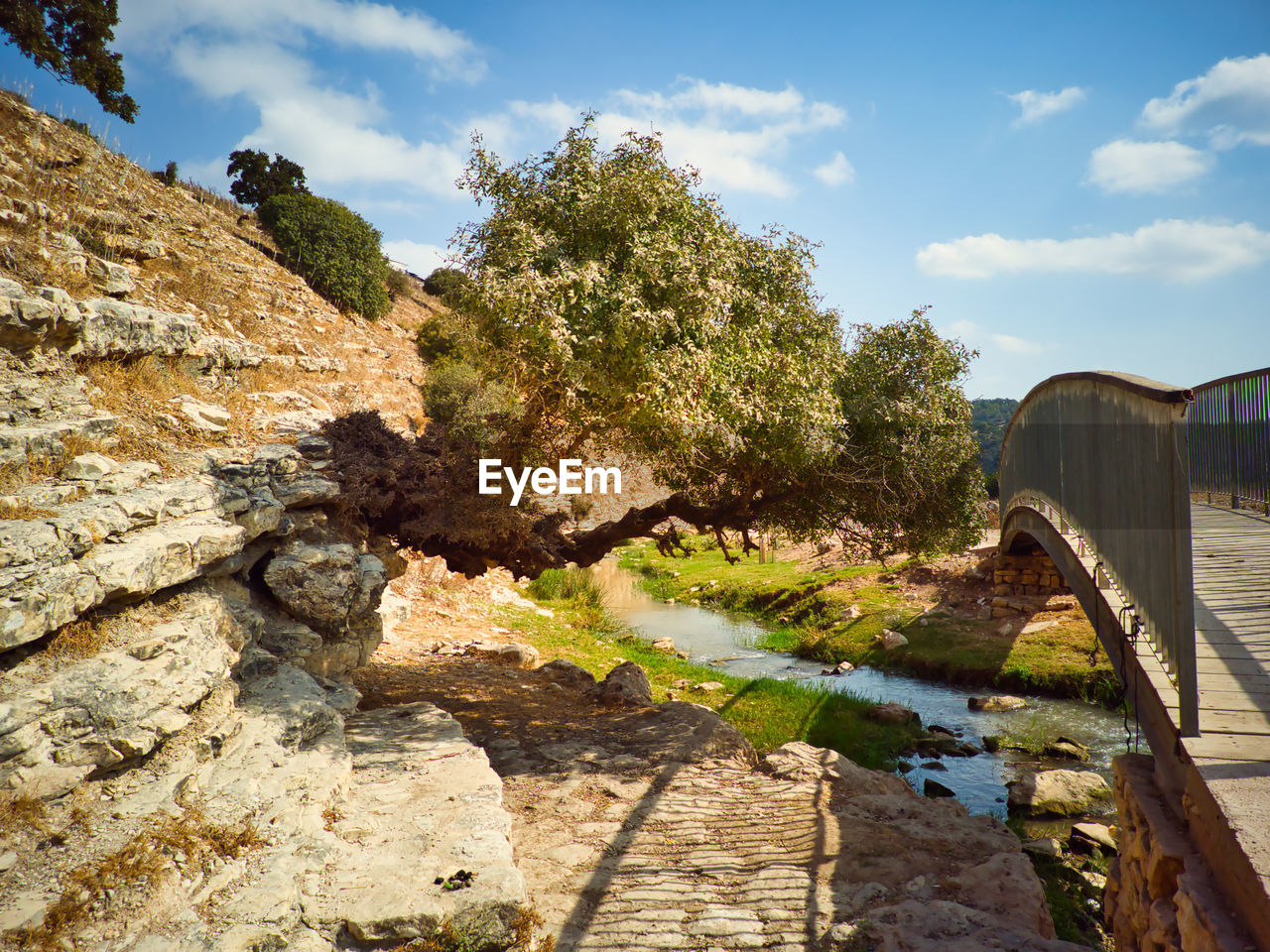 sky, nature, water, bridge, rock, plant, river, cloud, landscape, tree, architecture, no people, built structure, environment, travel destinations, scenics - nature, travel, beauty in nature, outdoors, sunlight, day, footpath, tourism, tranquility, autumn, land, transportation, coast, non-urban scene