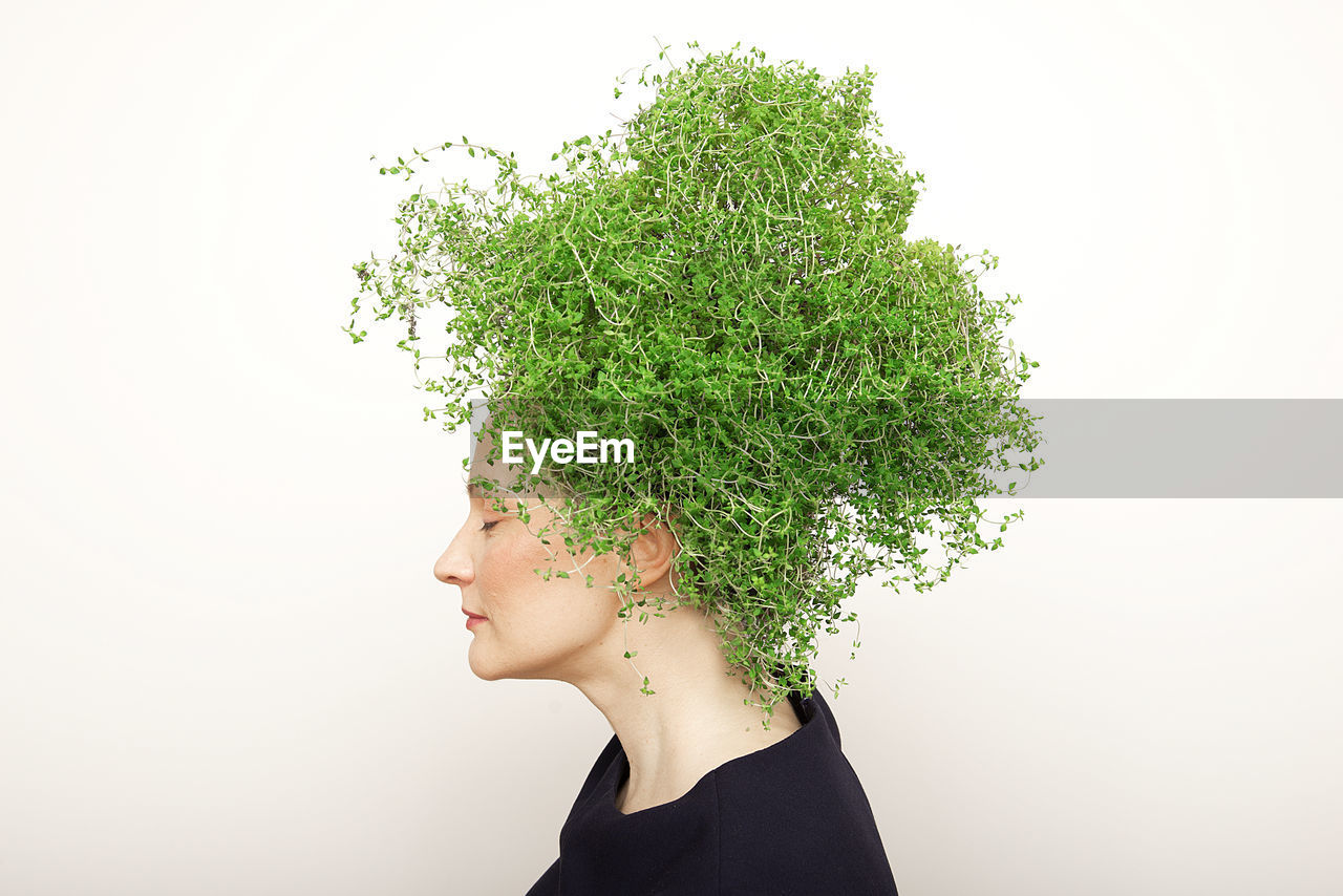 Close-up of young against with plants on head against white background