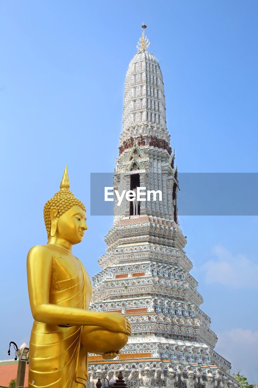 Statue of buddha and temple against building