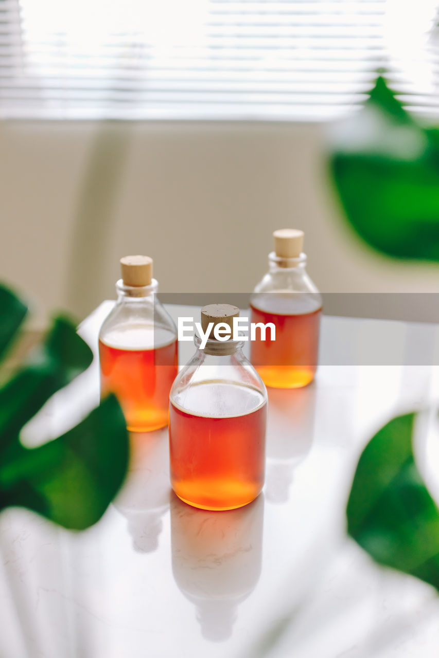 Close-up of honey in bottles on table against window