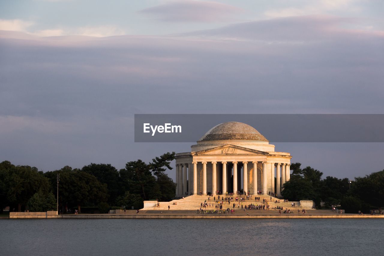 Lake against historic building during sunset