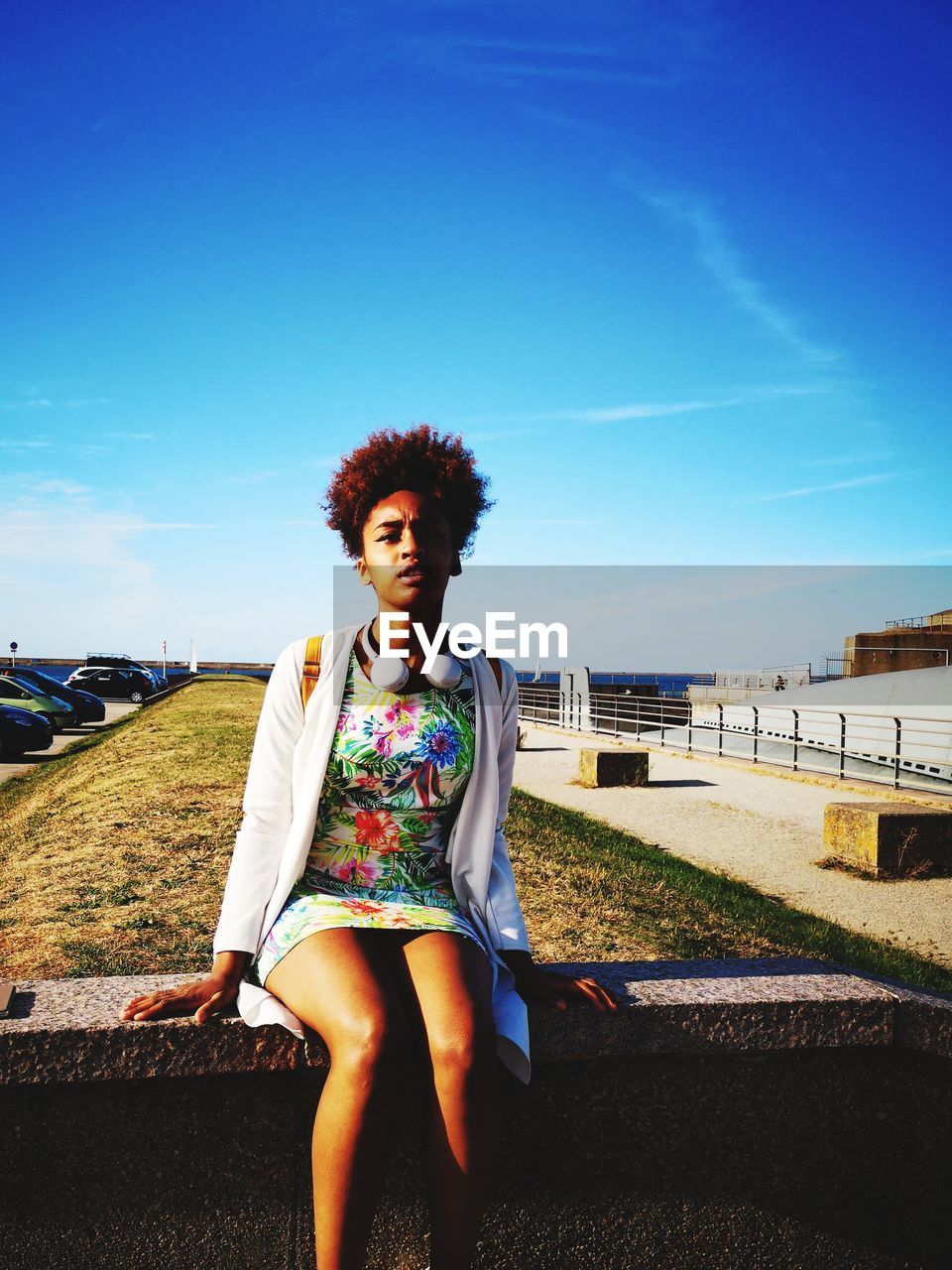 Portrait of woman siting on bench against blue sky