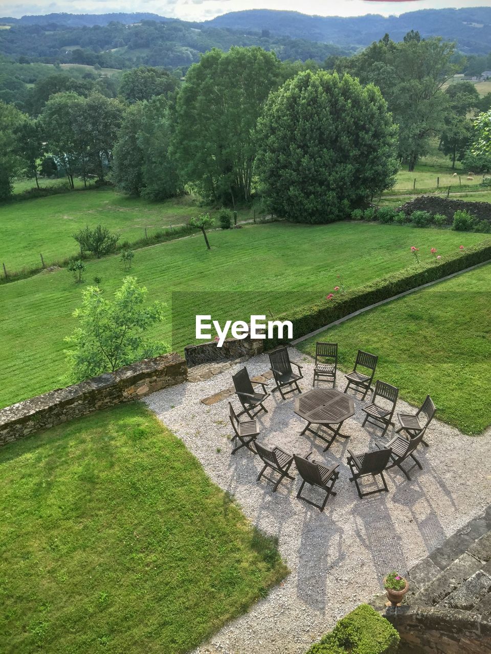 Empty chairs and table amidst green field